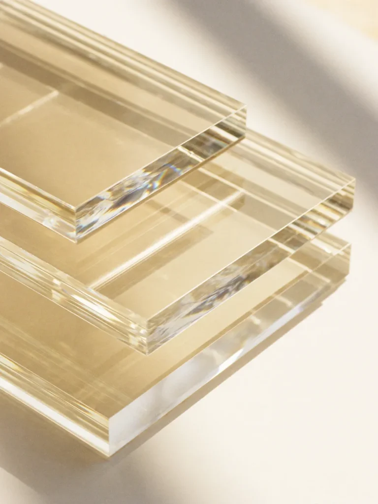Plaques de plexiglas acrylique transparent empilées, tranches polies sur fond crème